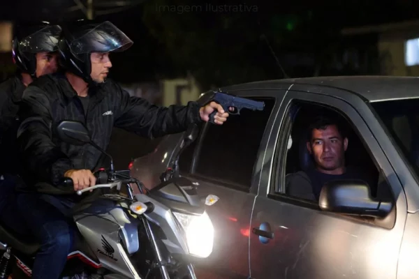 dois homens armados em uma moto, apontando uma pistola para o motorista de um carro