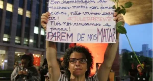mulher segurando cartaz sobre combate a violência contra as mulheres