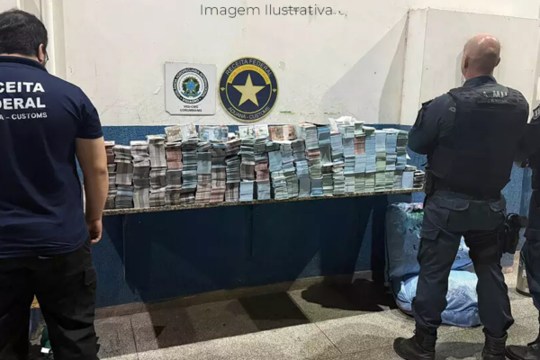 Policiais e agente da receita federal em frente a milhões em notas falsificadas