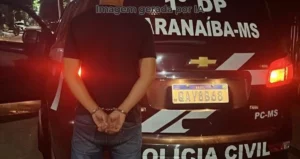 homem algemado em frente a uma viatura da Polícia Civil de Paranaíba-MS