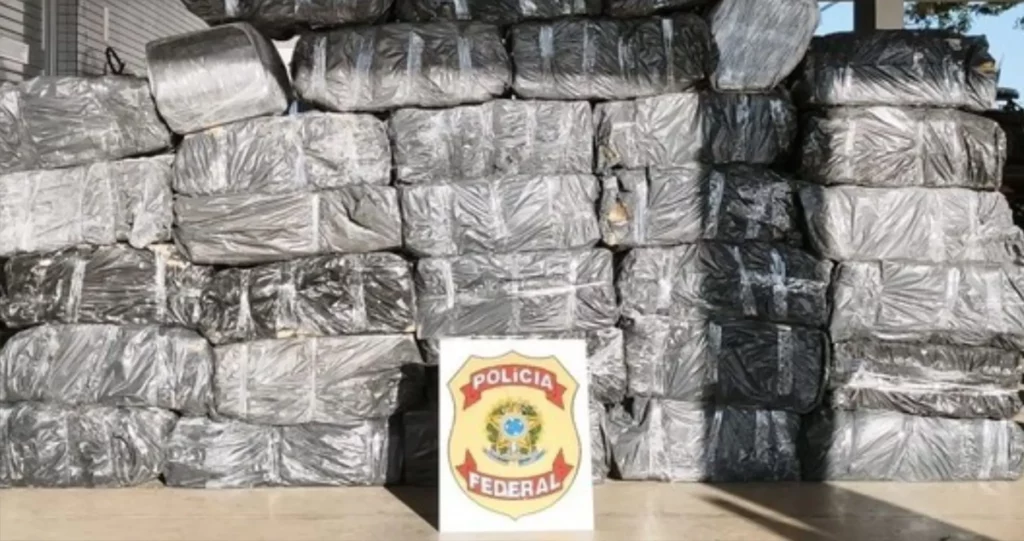 Pilha de centenas de tabletes de maconha embalados em sacos plásticos pretos apreendidos pela Polícia Federal em caminhão.